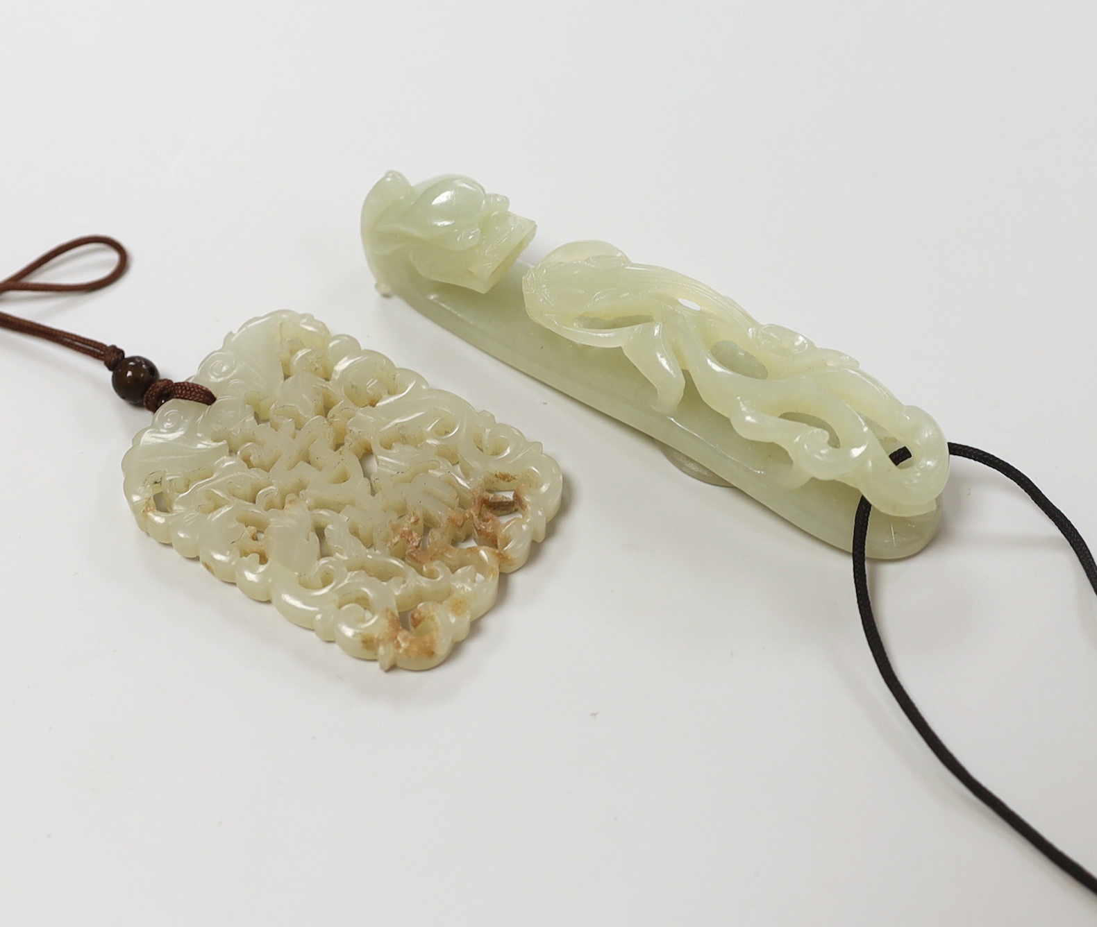 A Chinese pale celadon jade belt hook, 18th / 19th century and a similar 19th century pendant, pendant 5.5 cm long